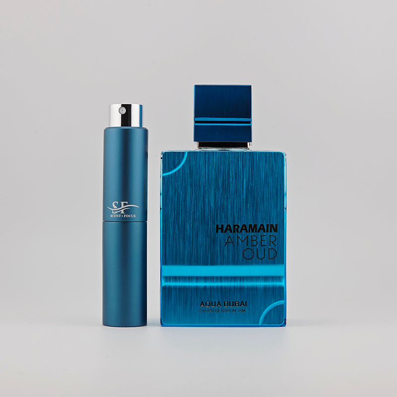 Al Haramain Amber Oud Aqua Dubai with travel-size decant atomizers on a plain background
