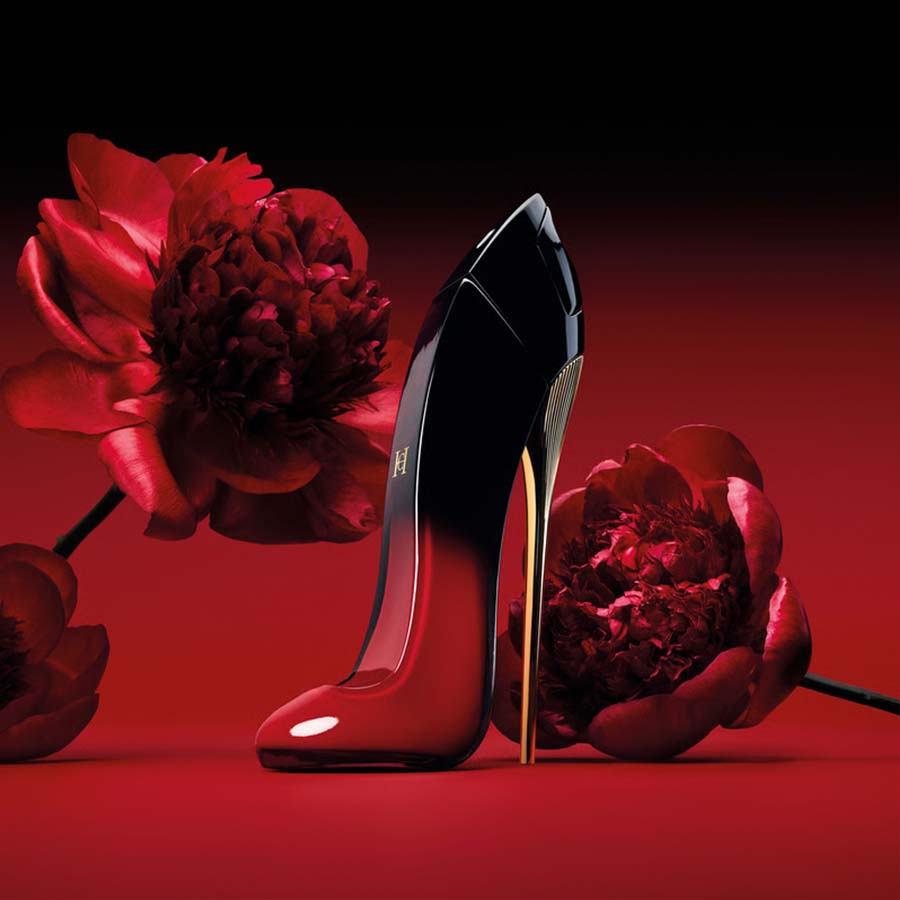 Carolina Herrera Very Good Girl Elixir Bottle On a Red Background With Red Florals