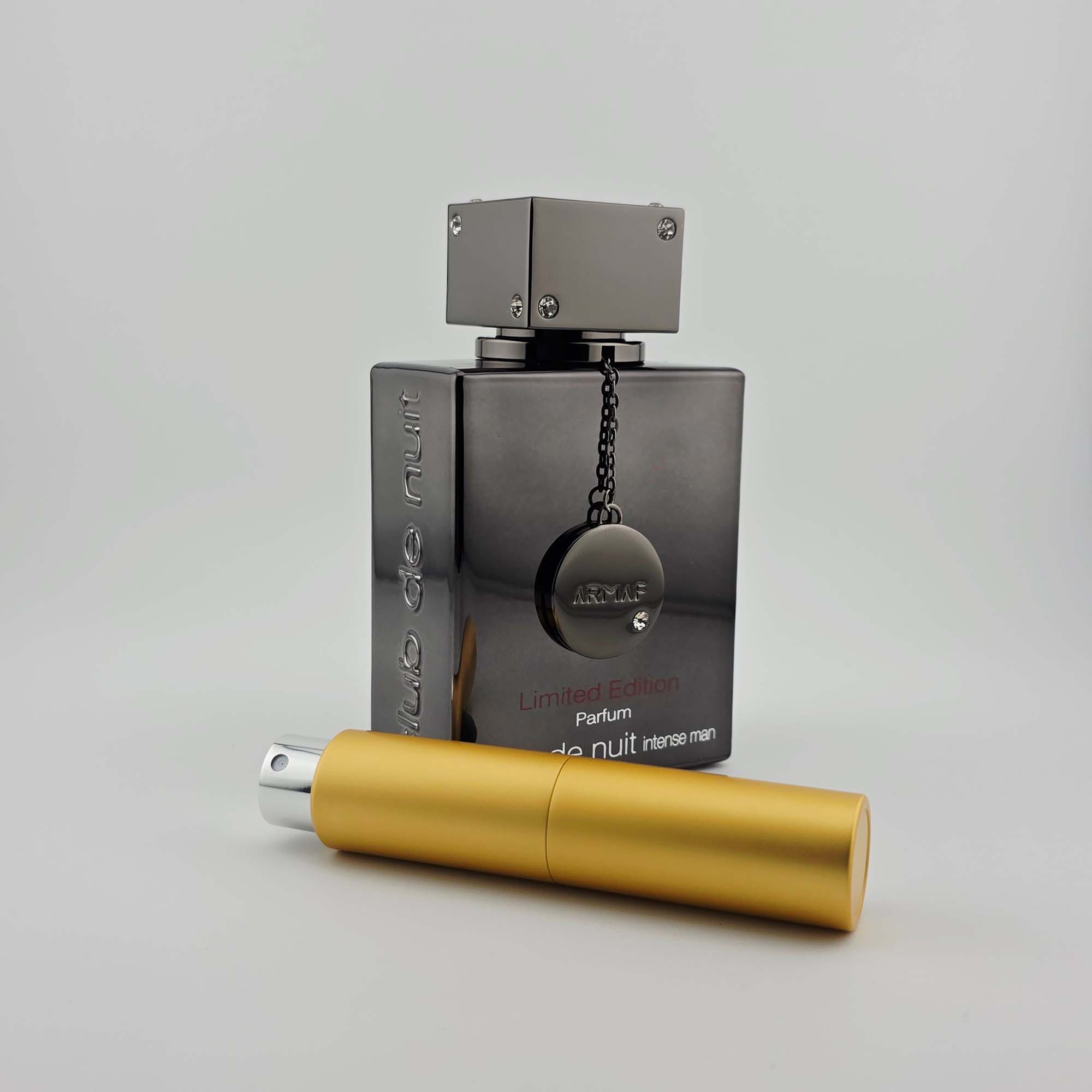 Armaf Club de Nuit Intense Man Limited Edition bottle with gold travel-size decant spray on a light background