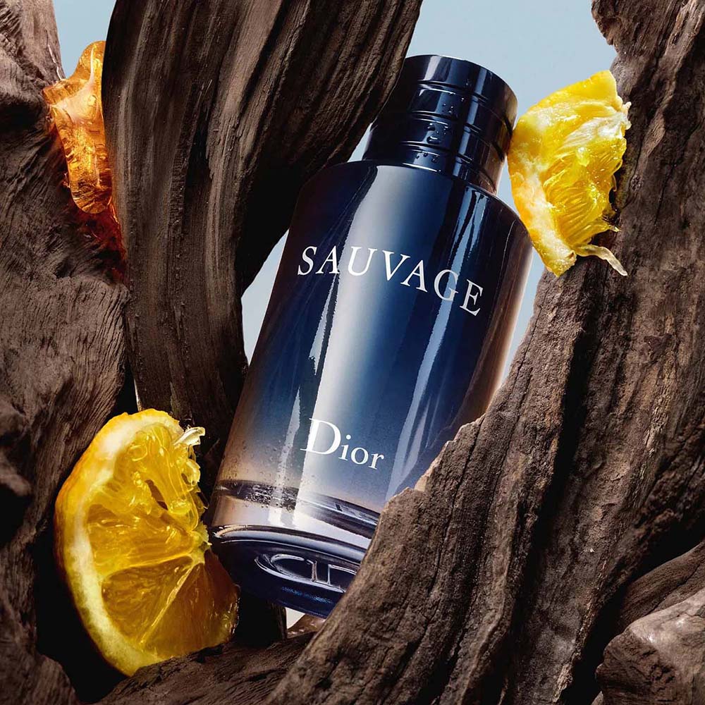 Dior Sauvage bottle nestled in dark wood with citrus and amber accents
